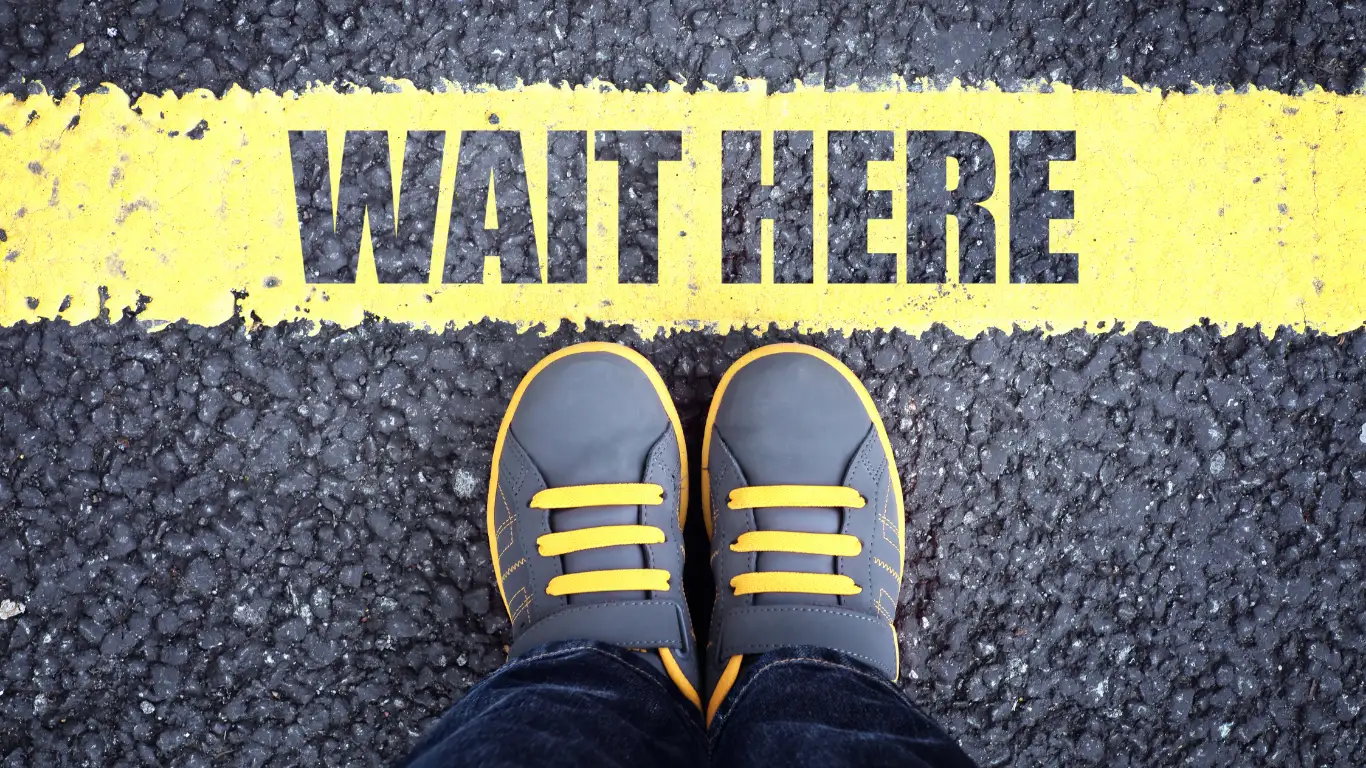 A child&rsquo;s shoes at a painted &lsquo;Wait Here&rsquo; line on pavement