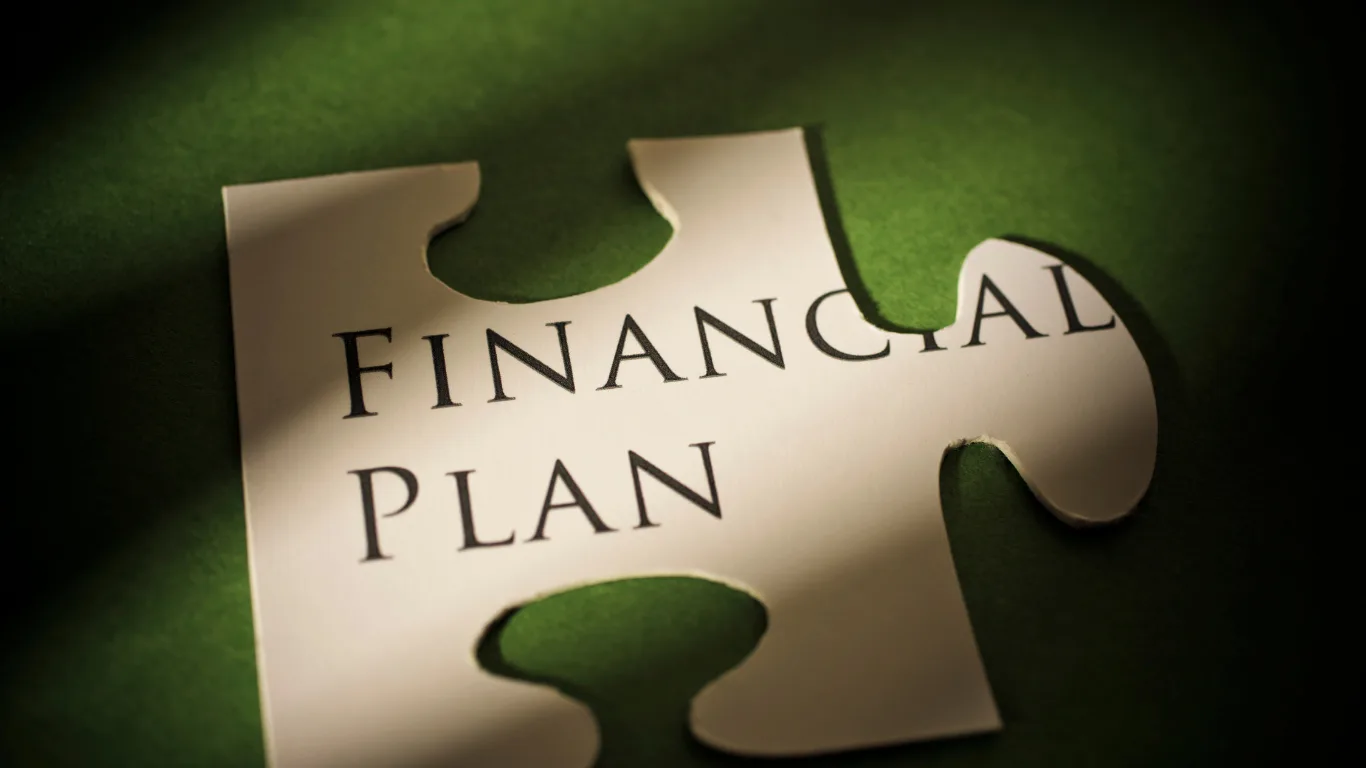A jigsaw puzzle piece with the words &lsquo;Financial Plan&rsquo; printed on it, set against a dark green background